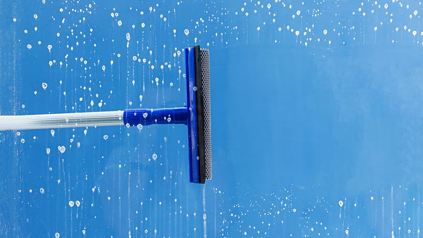 Window cleaning service squeegee pulling away soap suds 